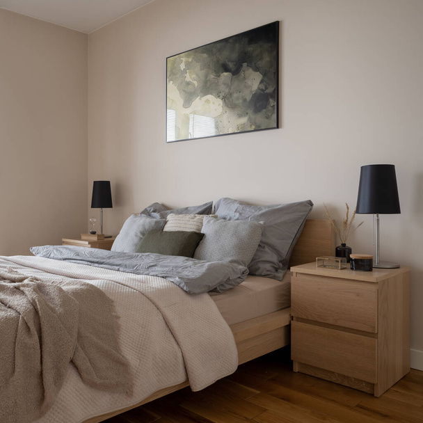 Comfortable and bright bedroom with big cozy bed, two wooden bedside tables with lamps and nice decorations - Fotó, kép