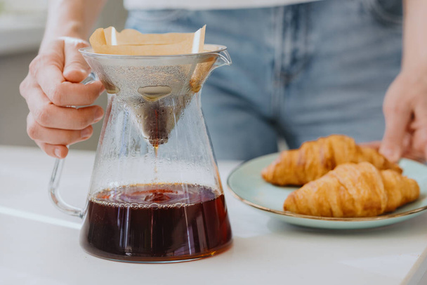  coffee in the morning, European woman brews coffee and drinks it, croissants and coffee for breakfast - Φωτογραφία, εικόνα