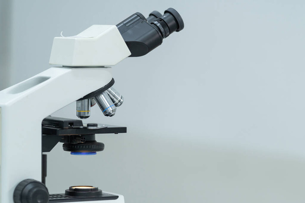 Nahaufnahme und selektive Fokusaufnahme eines Mikroskops, medizinischer Reagenzgläser mit Flüssigkeit und anderer moderner Laborgeräte in einem Laborraum. Archivbild Bildung - Foto, Bild