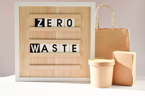 A board with the inscription Zero waste. Cardboard box with natural light and shadows. Paper packaging for food products. Recyclable paper. - Фото, изображение