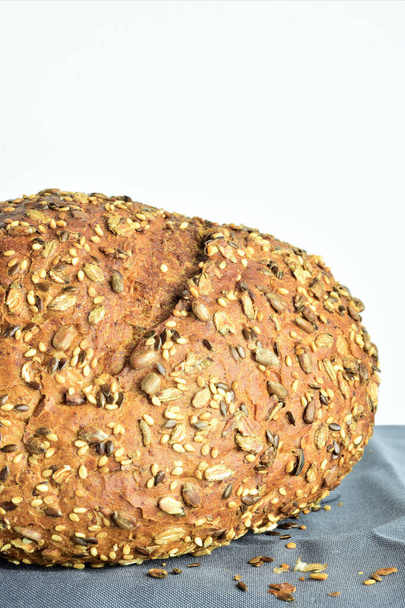 Θέα προς Ζενίθ. Πολύσπορο ψωμί, σε μια χάρτινη σακούλα Κραφτ σε ένα ανοιχτόχρωμο ρουστίκ τραπέζι. Υλικά και σκεύη. - Φωτογραφία, εικόνα