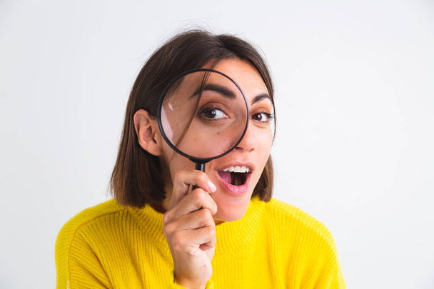 Pretty woman in yellow sweater on white background held magnifier happy positive playful - Photo, Image