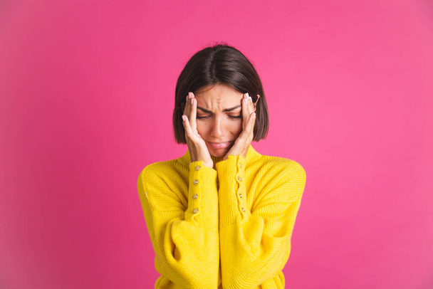 Beautiful woman in bright yellow sweater isolated on pink background stressful crying depression - Foto, Imagem