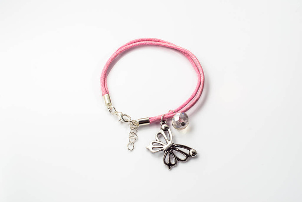 Close-up of handmade bracelet made with pink leather, crystal glass and butterfly pendant isolated on white background. - Foto, imagen