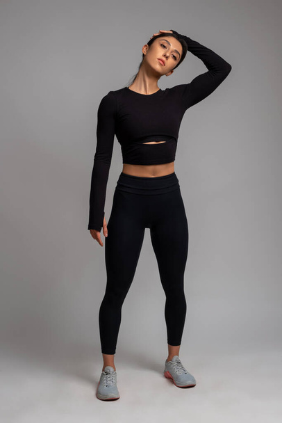 Sportlerin macht Dehnübungen auf grauem Hintergrund - Foto, Bild