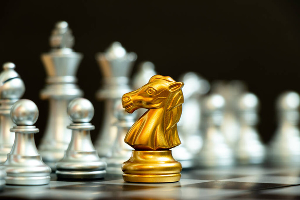 Złoty rycerz w szachach twarz gry z innym srebrnym zespołem na czarnym tle (Koncepcja strategii firmy, zwycięstwo biznesowe lub decyzja) - Zdjęcie, obraz