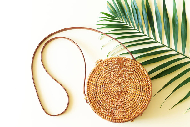 Trendy rattan straw round bag and tropical palm leaf top view - Φωτογραφία, εικόνα