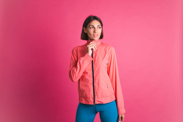 Young fit woman in sport wear jacket on pink background - Photo, image