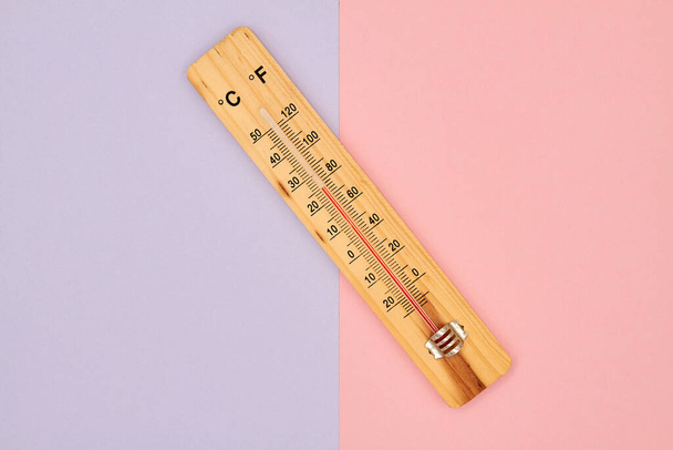 Zbliżenie zdjęcie drewnianego termometru alkoholu w gospodarstwie domowym pokazującego temperaturę w stopniach Celsjusza na kolorowym tle. - Zdjęcie, obraz