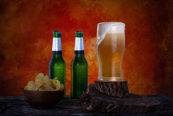 Ποτήρι μπύρας με αφρό δίπλα σε δύο πράσινα μπουκάλια μπύρας lager. Μπουκαλάκια και γυάλινα με σταγόνες νερού.  - Φωτογραφία, εικόνα