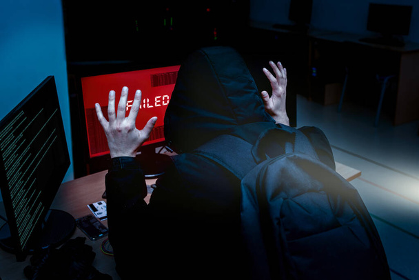 Internetowy haker próbujący włamać się do serwerów korporacyjnych aresztowanych nocą przez policję. Portret poddanego hakera komputerowego, który podniósł ręce pod latarkę. nie udało się włamać system - Zdjęcie, obraz