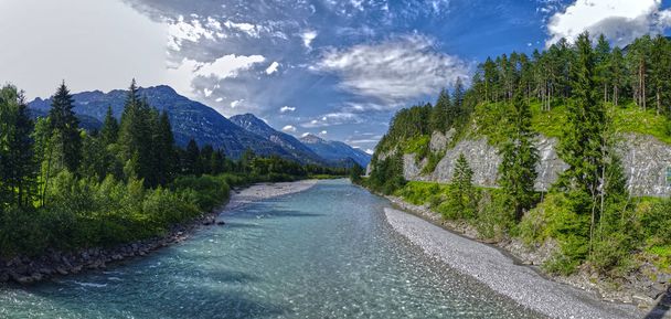 A beautiful shot of Lech river surrounded by scenic landscape field and mountain in Austria - Foto, Imagen