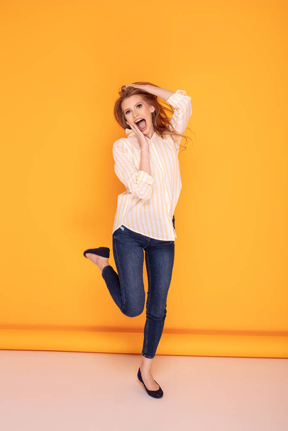 happy beautiful jumping woman on yellow background - 写真・画像