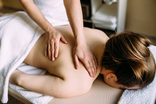Massage therapeut doet massage op het vrouwelijk lichaam in de spa. - Foto, afbeelding