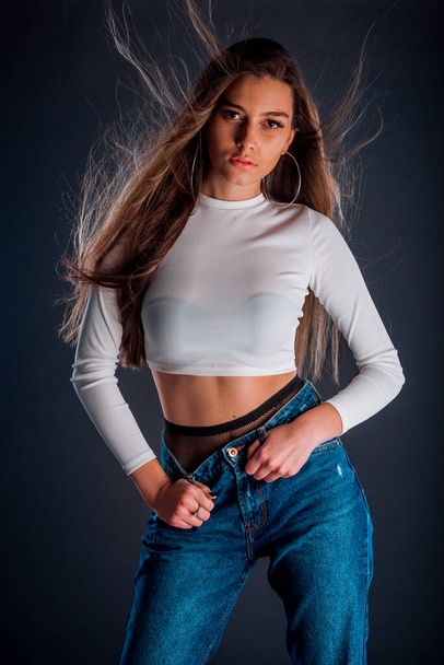 Body shot of a stylish woman posing in blue trendy jeans and long blouse - Fotografie, Obrázek