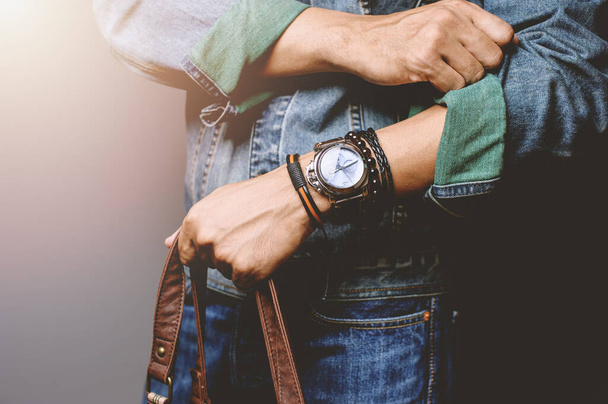 ブレスレットや腕時計を身に着けているジャンジャケットの男、男性アクセサリーのカジュアルなスタイル。フィールドの浅い深さ. - 写真・画像
