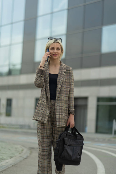 Mujer de negocios está sonriendo mientras habla por teléfono con sus socios - Foto, Imagen
