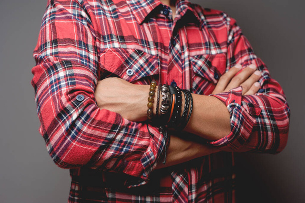 The man in red shirt wearing bracelets, casual style of men accessories. Shallow depth of field. - Photo, Image
