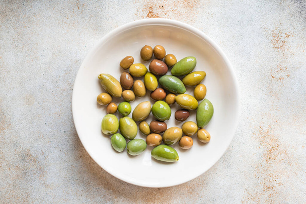 green olives in bowl on stone background. top view. - Zdjęcie, obraz