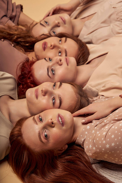 Portrait of young ladies feeling calmness and tenderness, laying down on floor - 写真・画像