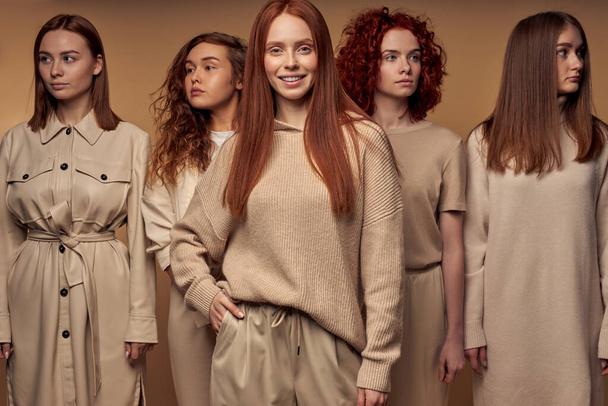 Attractive red-haired models in beige casual outfit stand isolated on beige - Φωτογραφία, εικόνα