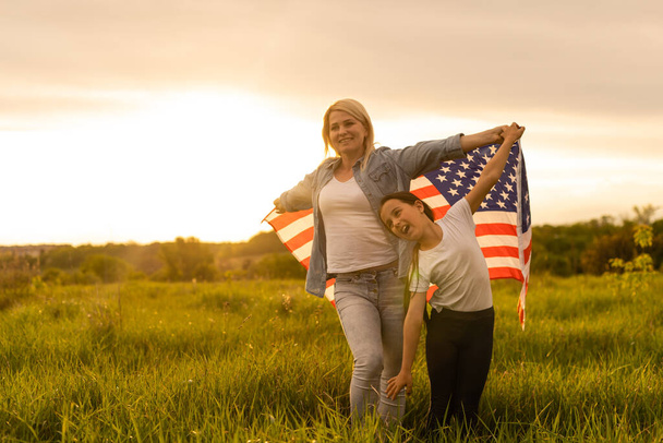 Mother and daughter with American Flag in a beautiful field - Photo, Image