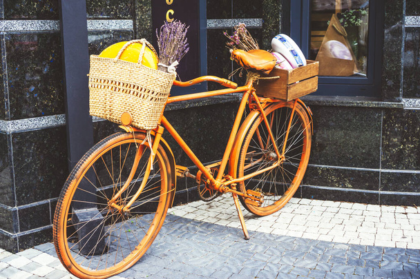 Vélo rétro orange avec panier en paille tricoté avec tête de fromage et bouquet de lavande sèche à l'intérieur fixé au guidon. Concept d'éco-matériaux naturels, shopping, sans plastique, zéro wast. - Photo, image