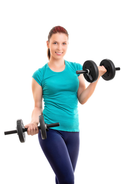 Fit attractive young smiling woman in sportswear doing dumbbell concentration curls, isolated on white background. Fitness and healthy lifestyle concept. Young woman exercising with dumbbells. - Foto, immagini