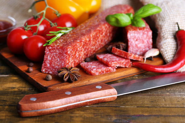 Tasty salami sausage and spices on wooden background - Valokuva, kuva