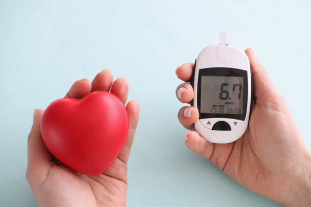 Small heart and glucometer with indicators held in hand - Foto, Bild