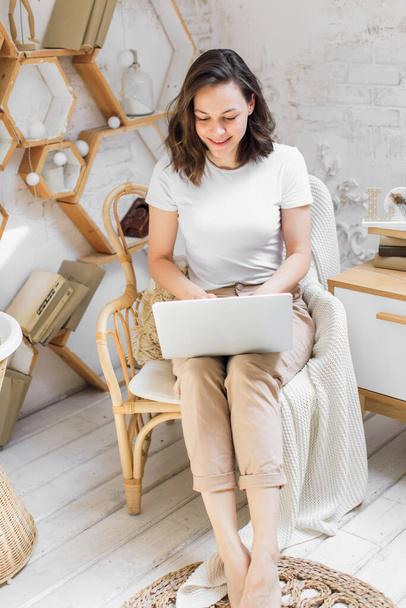 a young attractive woman in a bright modern apartment uses a laptop to communicate or study online - Foto, Bild