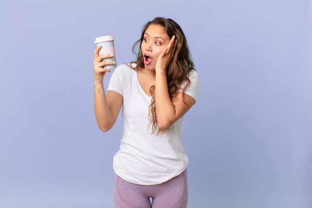 young pretty woman feeling happy, excited and surprised and holding a coffee - Foto, Bild