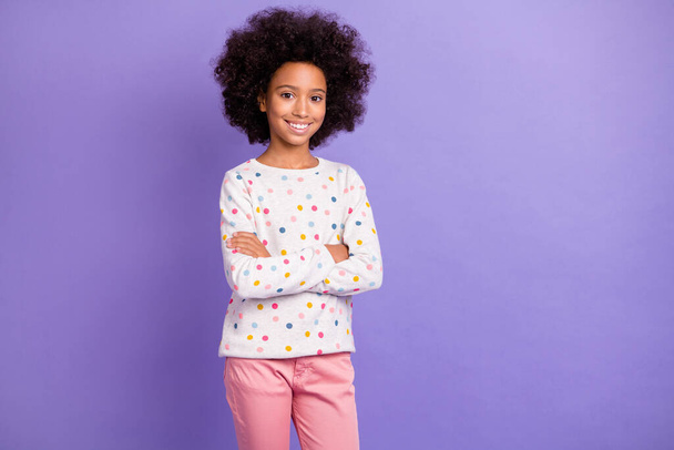 Photo of charming afro american little girl crossed hands wear pink pants isolated on violet color background - 写真・画像