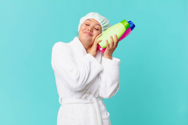 young pretty woman wearing bathrobe and holding a clean product bottle - Foto, immagini