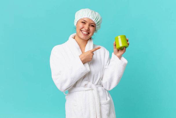 young pretty woman wearing bathrobe and holding a clean product bottle - Фото, зображення