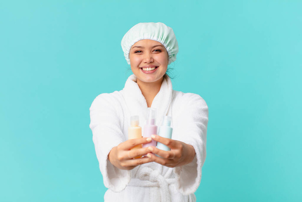 young pretty woman wearing bathrobe and holding a clean product bottle - Foto, immagini