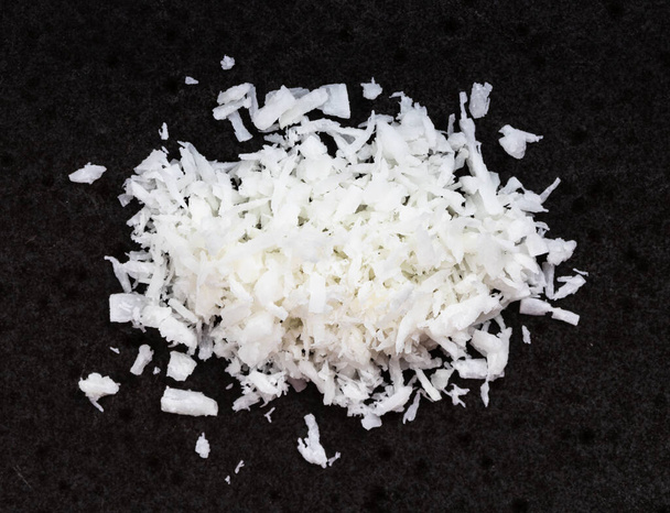 top view of pile of coconut flakes close up on black ceramic plate - Fotografie, Obrázek