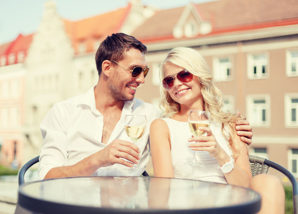 smiling couple in sunglasses drinking wine in cafe - Foto, Bild