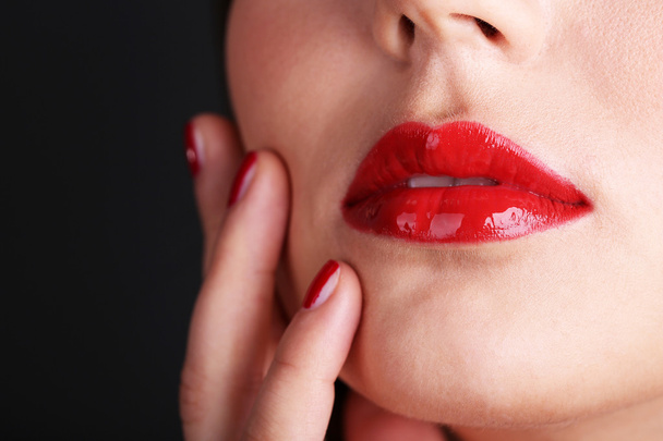 Girl with red lips and nails on dark background - Foto, afbeelding