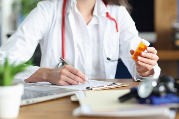 Doutor preenche documentos médicos com caneta e contém pílulas em sua mão - Foto, Imagem