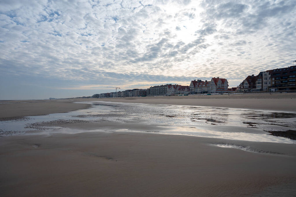Χαμηλή περίοδος βόλτα στην κίτρινη αμμώδη παραλία στη μικρή βελγική πόλη De Haan ή Le Coq sur mer, προορισμός διακοπών πολυτελείας, καλοκαιρινές διακοπές την ηλιόλουστη μέρα - Φωτογραφία, εικόνα
