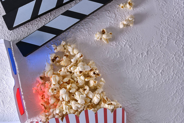 paper cup with popcorn, clapper board and 3D glasses on white background copy space. top view. - Photo, Image