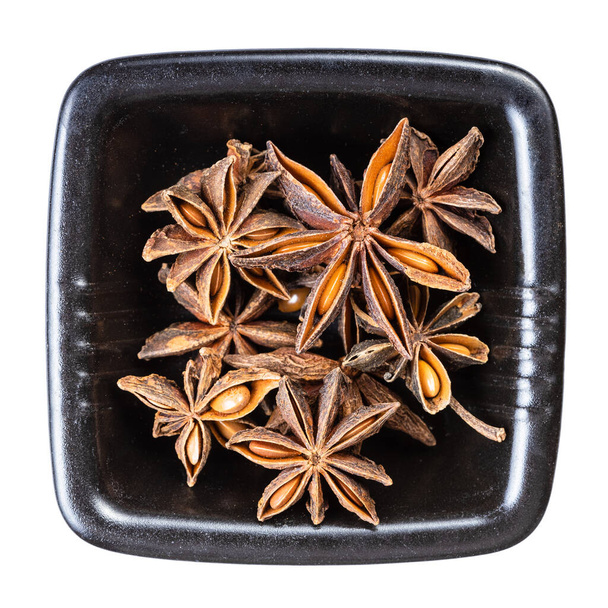 вид зверху на сушені зірки анісу (badian) фрукти в чорній мисці ізольовані на білому тлі
 - Фото, зображення