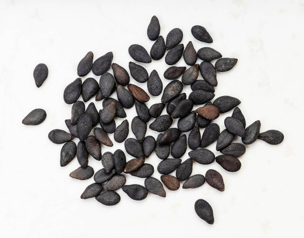 kilka nasion czarnego sezamu z bliska na szarej ceramicznej płytce - Zdjęcie, obraz