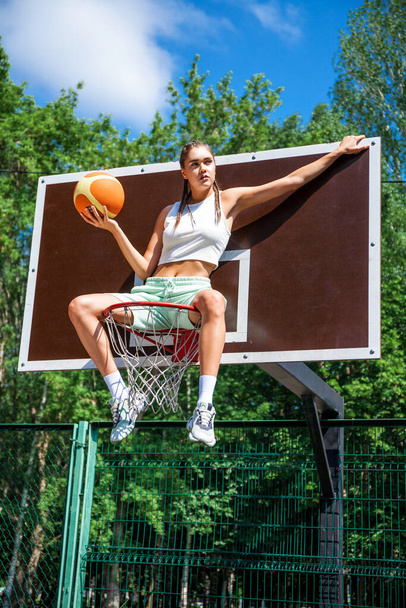 Young beautiful brunette girl posing on the basketball court - Fotoğraf, Görsel