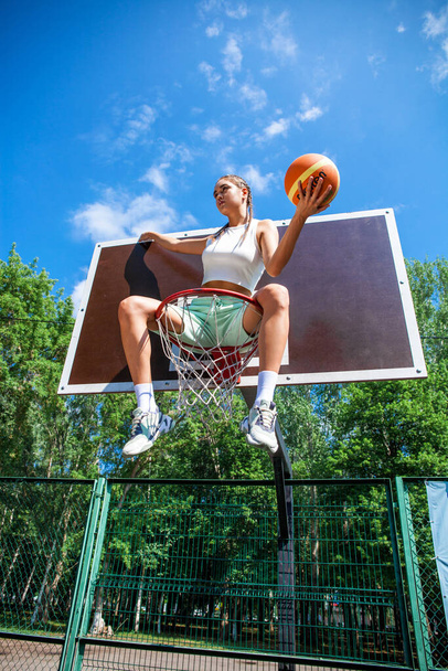 Young beautiful brunette girl posing on the basketball court - Fotó, kép