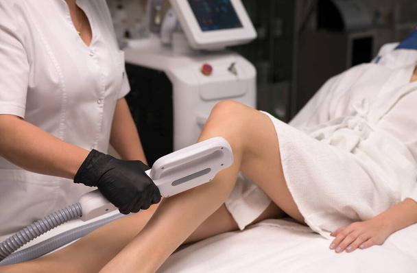 Hair removal cosmetology procedure from a therapist at cosmetic beauty spa clinic. Laser epilation and cosmetology. - Foto, afbeelding
