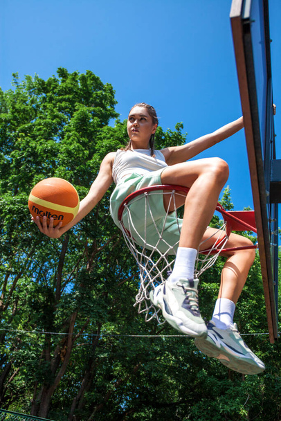 Young beautiful brunette girl posing on the basketball court - Фото, зображення