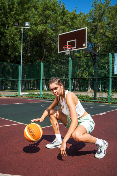 Young beautiful brunette girl posing on the basketball court - Fotografie, Obrázek