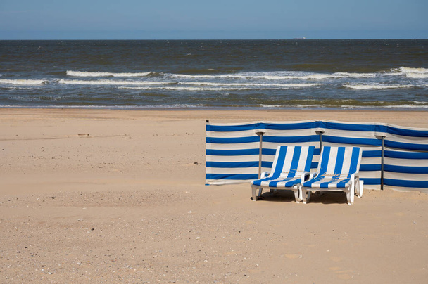 Lege blauw-witte ligbedden op geel zandstrand in klein Belgisch stadje De Haan of Le Coq sur mer, luxe vakantiebestemming, zomervakantie - Foto, afbeelding